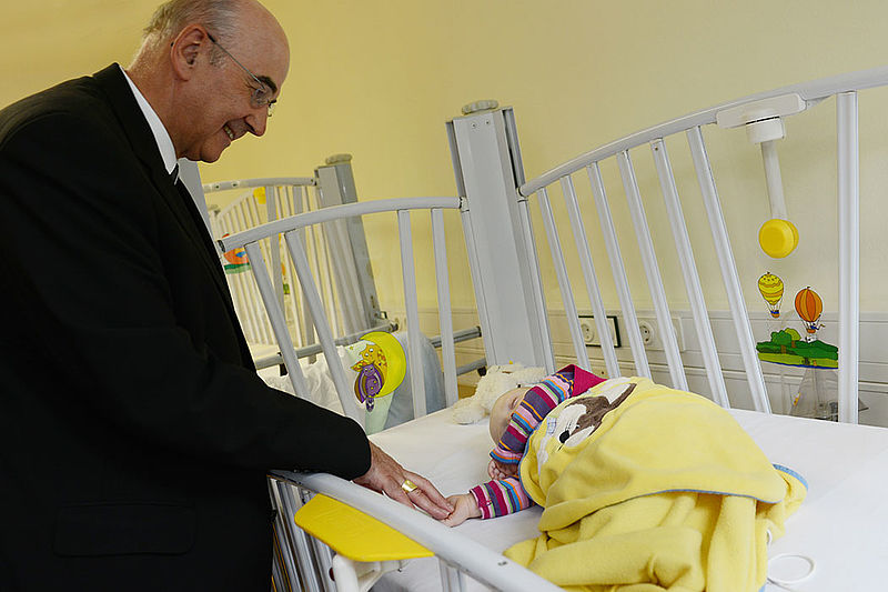 Der Bischof am Krankenbett eines Säuglings