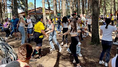 Junge Menschen tanzen ausgelassen in einem Wald.