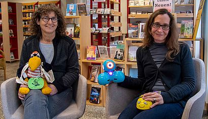 Zwei Frauen sitzen in einer Bücherei.