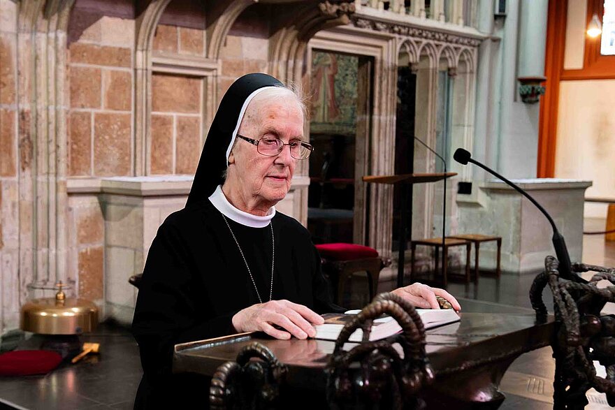 Eine Ordensfrau steht am Lesepult einer Kirche und schaut in ein Buch. Eine Ordensfrau steht am Lesepult einer Kirche und schaut in ein Buch.