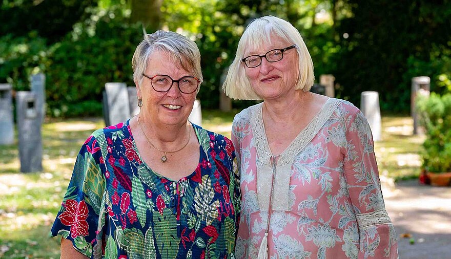 Zwei Frauen stehen auf einem Friedhof. Zwei Frauen stehen auf einem Friedhof.