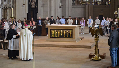 Die Religionslehrkräfte stehen im Halbkreis hinter dem Altar des St.-Paulus-Doms. Im Vordergrund ist Bischof Genn zu sehen.