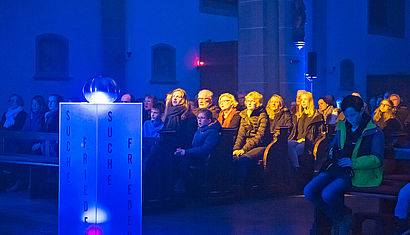 Der St.-Johannes-Kirche in Oelde leuchtet blau, rund 280 Besucher sitzen in den Bänken. 