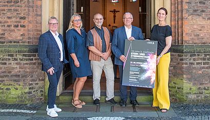 Fünf Personen stehen vor einer Kirche.