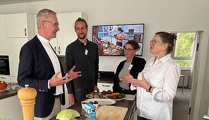 Diözesanadministrator Antonius Hamers unterhält sich in einer Küche mit Mitarbeitenden des Hauses der Familie.