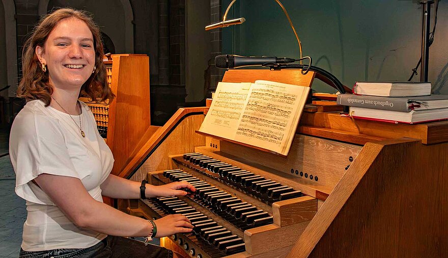 Eine junge Frau sitzt an einer Kirchenorgel.