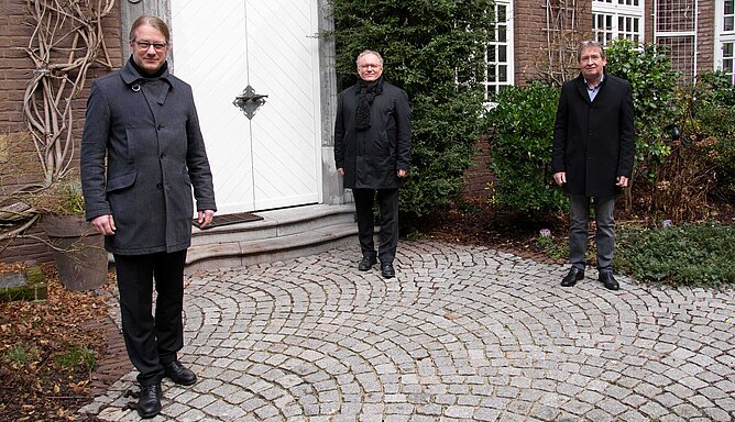 Drei Männer stehen im Atrium des Priesterhauses.
