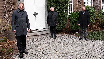 Drei Männer stehen im Atrium des Priesterhauses.