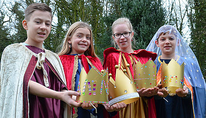 Die Sternsinger Sophia, Mila, Hannes und Henning präsentieren ihre goldenen Kronen. 