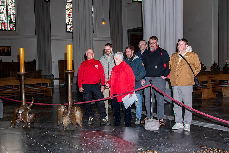 Mehrere Personen stehen im Xantener Dom und hören einer Gästeführerin zu.