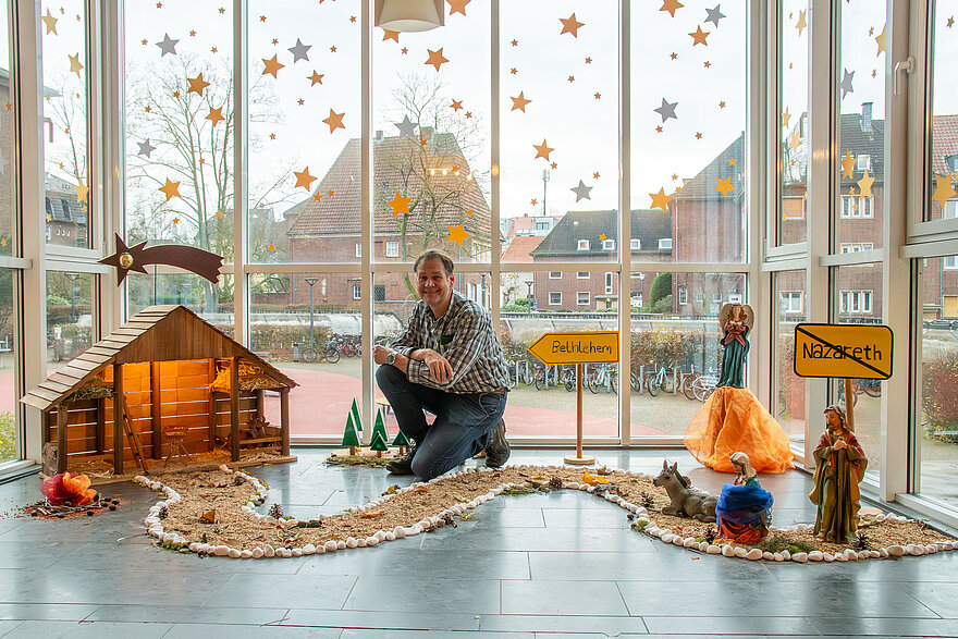 Haustechniker Ralf Orlowski inmitten seiner Krippe, die er aus Materialien der Turnhalle für die bischöfliche Marienschule gefertigt hat.
