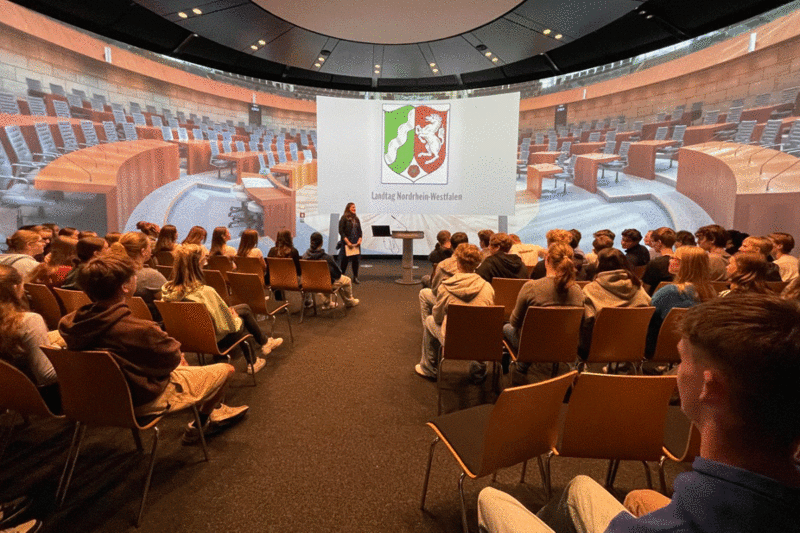 Eine Schülergruppe sitzt in einem Saal im Landtag.
