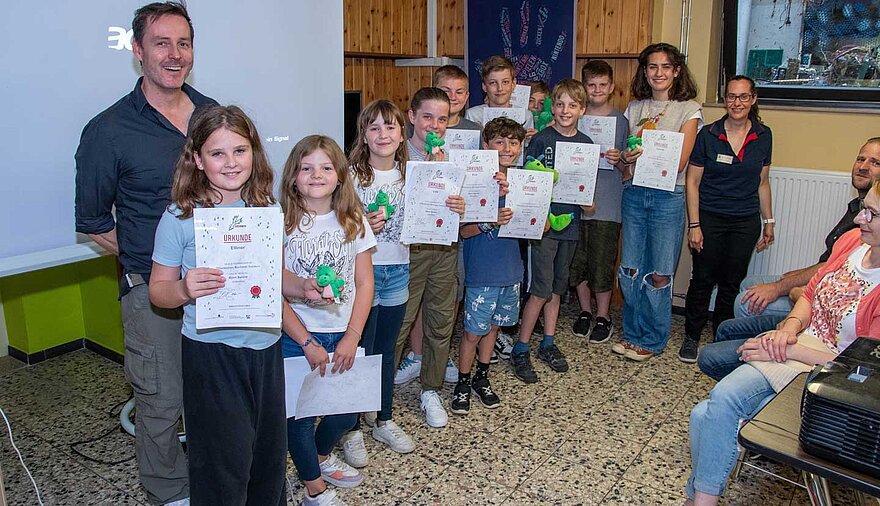 Viele Kinder stehen in einem Raum und haben Urkunden in der Hand