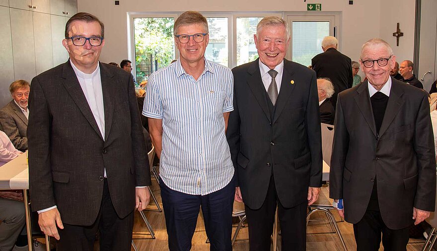 Vier Männer stehen nebeneinander in einem Raum.