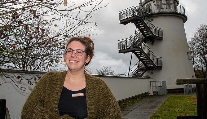 Eine Frau steht vor einem umgebauten Mühlenturm.