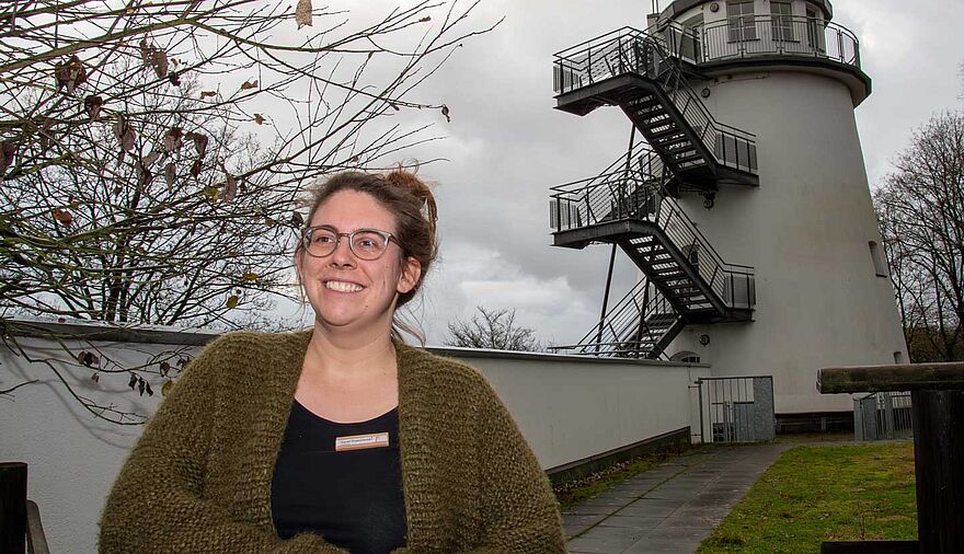 Eine Frau steht vor einem umgebauten Mühlenturm.