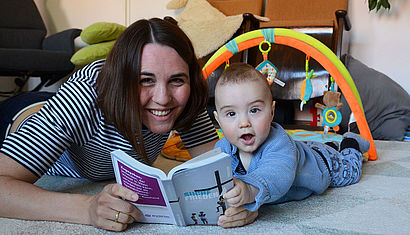 Katharina Krüger und ihr Sohn Justus liegen auf dem Boden und blättern im Katholikentags-Programm. 