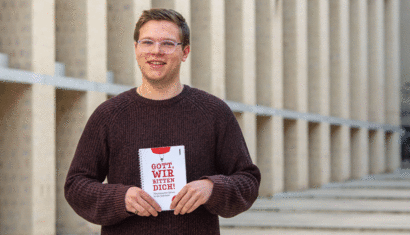 Ein Junger Mann hält ein Buch in den Händen.