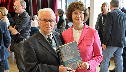 Paul Ley und Helga Giersiepen stehen nebeneinander und halten gemeinsam ein Exemplar des Buches "Die Inschriften der Stadt Xanten" in der Hand.