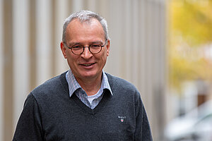 Schulseelsorger Johannes Gröger steht vor einem Gebäude. 
