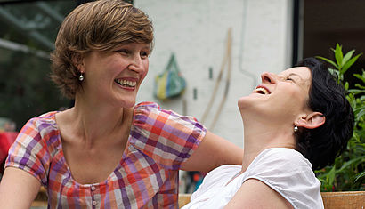 Frauen sitzen auf einer Bank und lachen 