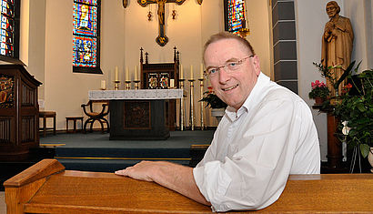 Peter Schneiders sitzt in der Kapelle der Kevelaerer Marienhospitals. Er lehnt sich nach hinten und blickt in die Kamera, während im Hintergrund der Altarraum zu sehen ist.
