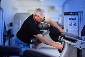 Andreas Smyrek stellt mit einem Schraubendreher ein Fitnessgerät ein.