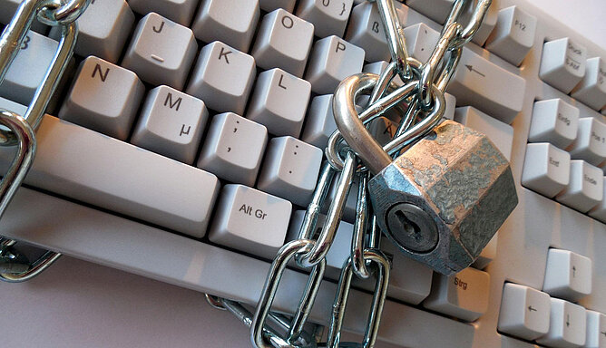 Eine Stahlkette mit Vorhängeschloss ist um eine Computertastatur gewickelt.