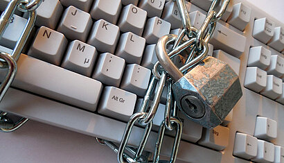 Eine Stahlkette mit Vorhängeschloss ist um eine Computertastatur gewickelt.