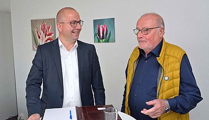 Patrick de Vries (links) und Edmund Raadts stehen an einem Tisch und unterhalten sich.