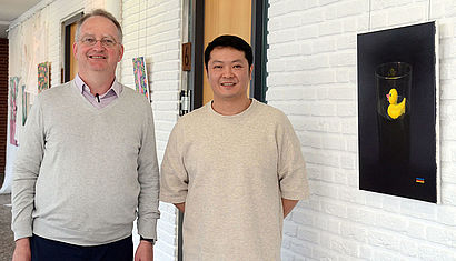 Dr. Gerd Blum und Künstler Qiwei Zang (von links) vor den Arbeiten des chinesischen Meisterschülers in der Akademie Franz Hitze Haus.