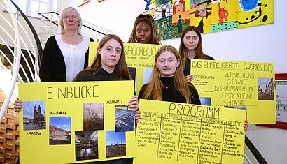 Vier Schülerinnen halten Plakate hoch, neben ihnen steht eine Lehrerin.