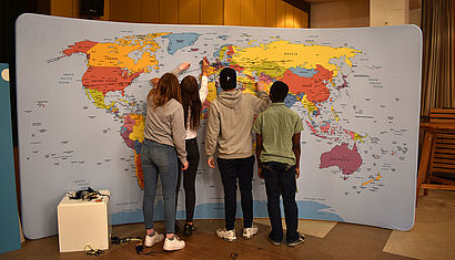 Schüler stehen vor einer Weltkarte