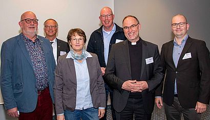 Eine Frau und fünf Männer stehen nebeneinander auf einem Gruppenfoto.