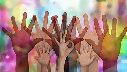 Mehrere nach oben gestreckte Hände vor einem farbigen Hintergrund