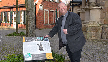 Propst Langenfeld steht neben dem neuen Hinweisschild.