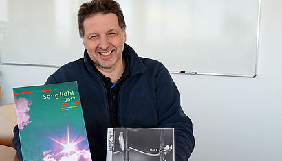 Daniel Franken zeigt die Liederbücher.