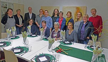 Mehrere Frauen und Männer, darunter Weihbischof Rolf Lohmann, sitzen oder stehen an einem schön gedeckten Tisch.