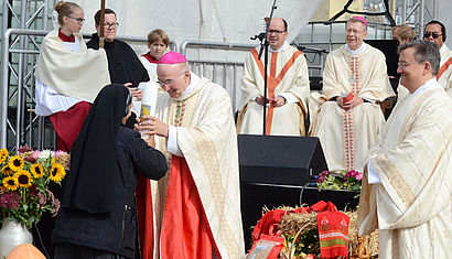 Bischof Dr. Felix Genn nimmt eine Kerze entgegen.