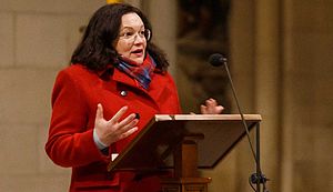 Andrea Nahles steht an einem Rednerpult im St. Paulus-Dom. Sie trägt einen roten Mantel und hält die Hände gestikulierend vor sich.