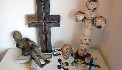 Verschiedene Keramikexponate wie Kreuze und ein Rosenkranz liegen auf einem Tisch.