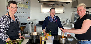 Sonja Schemmer, Yvonne Wilmer und Henrike Hallekamp stehen in einer Küche an einem Herd.
