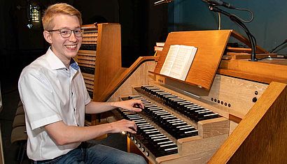 Ein junger Mann sitzt an einer Kirchenorgel.