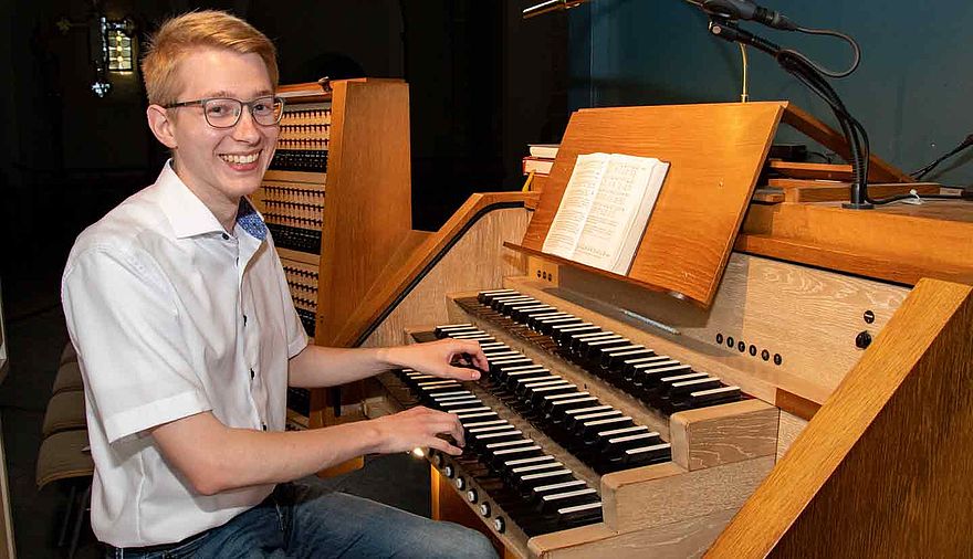 Ein junger Mann sitzt an einer Kirchenorgel.