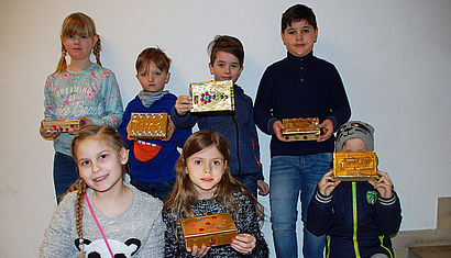 Kommunionkinder präsentieren ihre fertigen Schatzkisten.