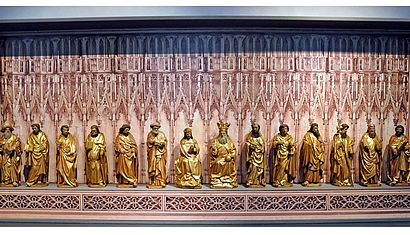 14 Heiligenfiguren stehen in einem Museum nebeneinander.
