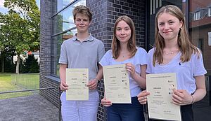 Noah Kortmann, Luisa Walcher und Jana Birkefeld stehen vor einem Gebäude. In den Händen halten sie Urkunden Noah Kortmann, Luisa Walcher und Jana Birkefeld stehen vor einem Gebäude. In den Händen halten sie Urkunden