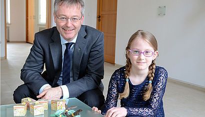 Generalvikar Dr. Norbert Köster sitzt neben Finja Delcour. Vor sich stehen die Sammelboxen und das Osternest. 