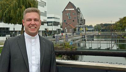 Porträtfoto von Pfarrer Philip Peters vor dem Campus der HRW.