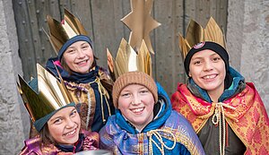 Vier Mädchen und Jungen stehen in Sternsingerkostümen gekleidet vor einer Tür. Vier Mädchen und Jungen stehen in Sternsingerkostümen gekleidet vor einer Tür.